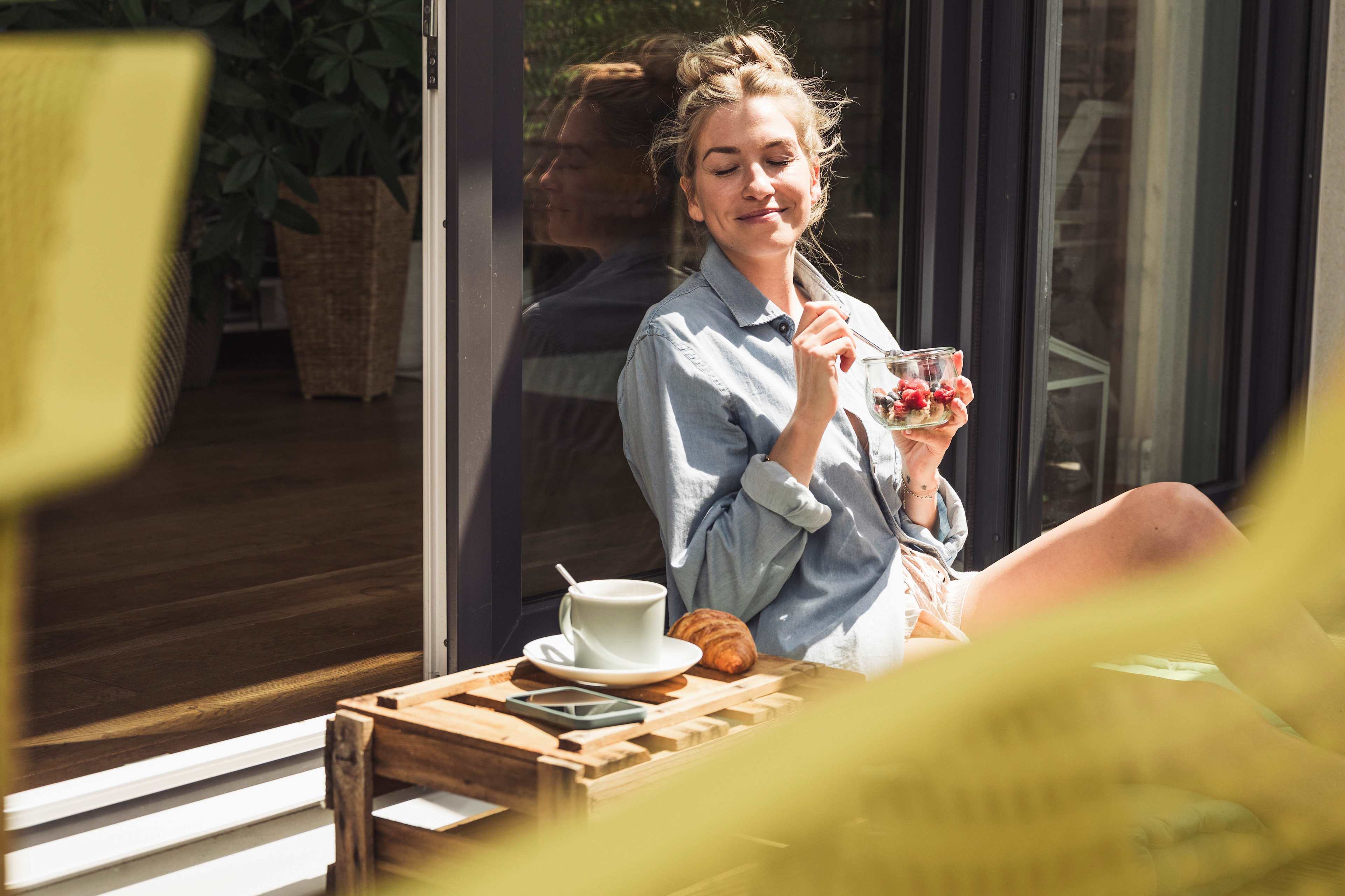 Wohlbefinden_Balkon_Sonne_Frau_Fruestueck_s_oew9q1