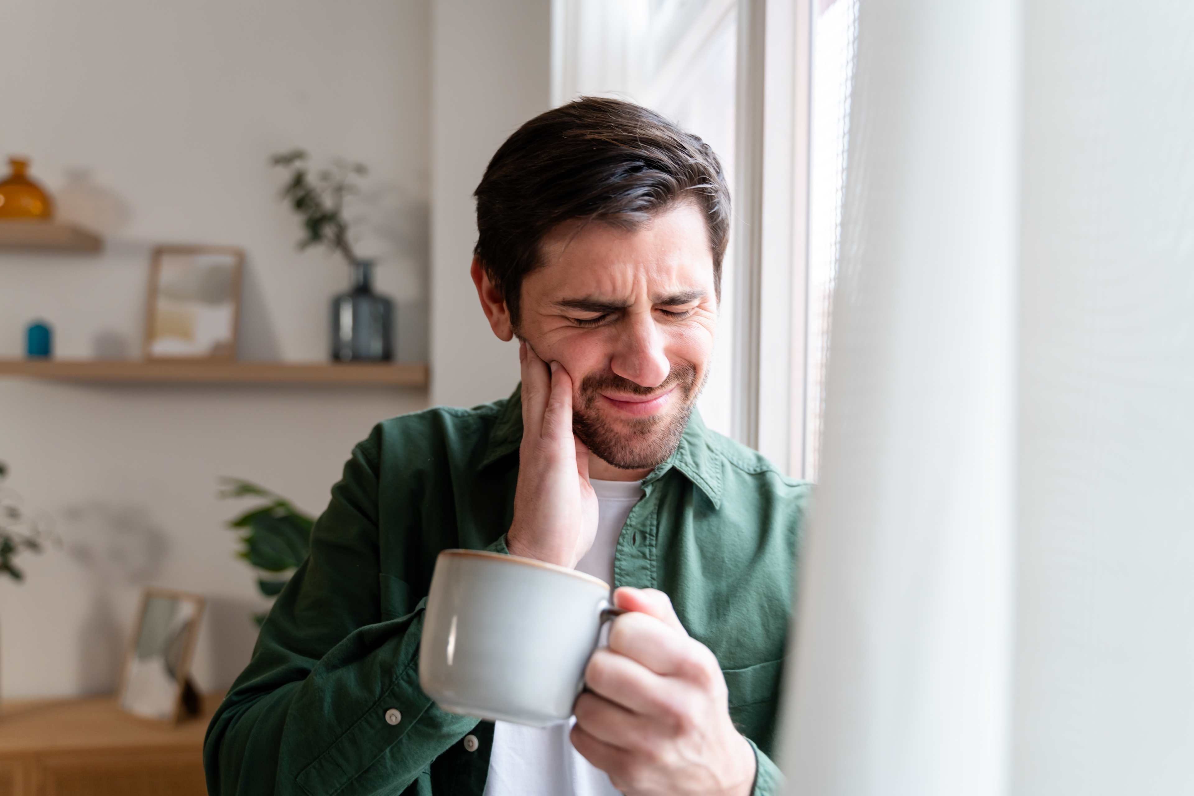 Mann_Wange_Schmerzen_Beschwerden_Aphthe_Zahn_Schmerzen_Tasse